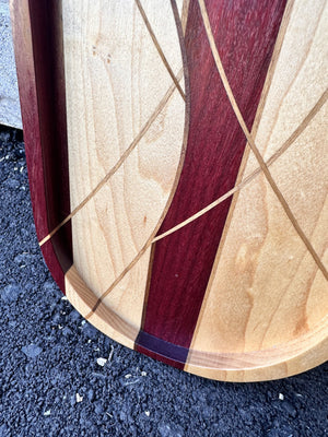 Close-up of the maple swirl tray's raised lip, purpleheart stripe and thin walnut inlay lines